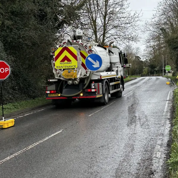 Lorry on a road passing through a stop/go sign.