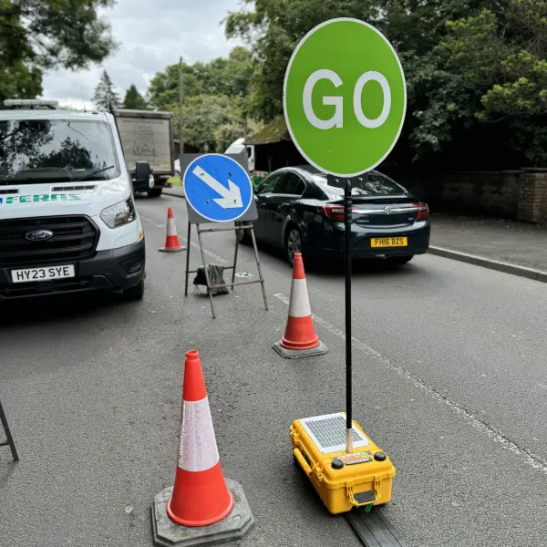 Car traffic on a road passing through a stop/go sign.